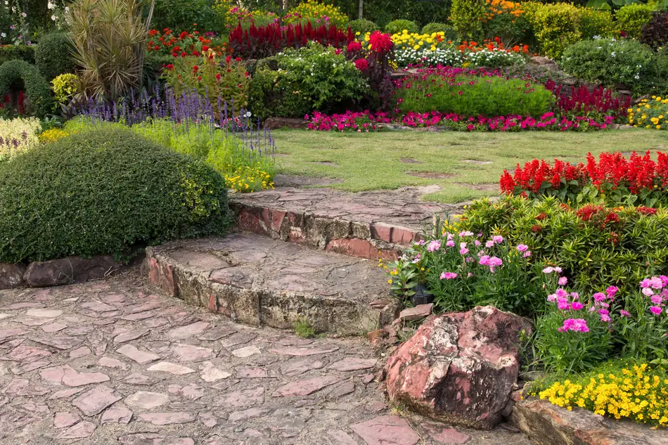 Landscaped garden with colorful flower beds and a stone paver path
