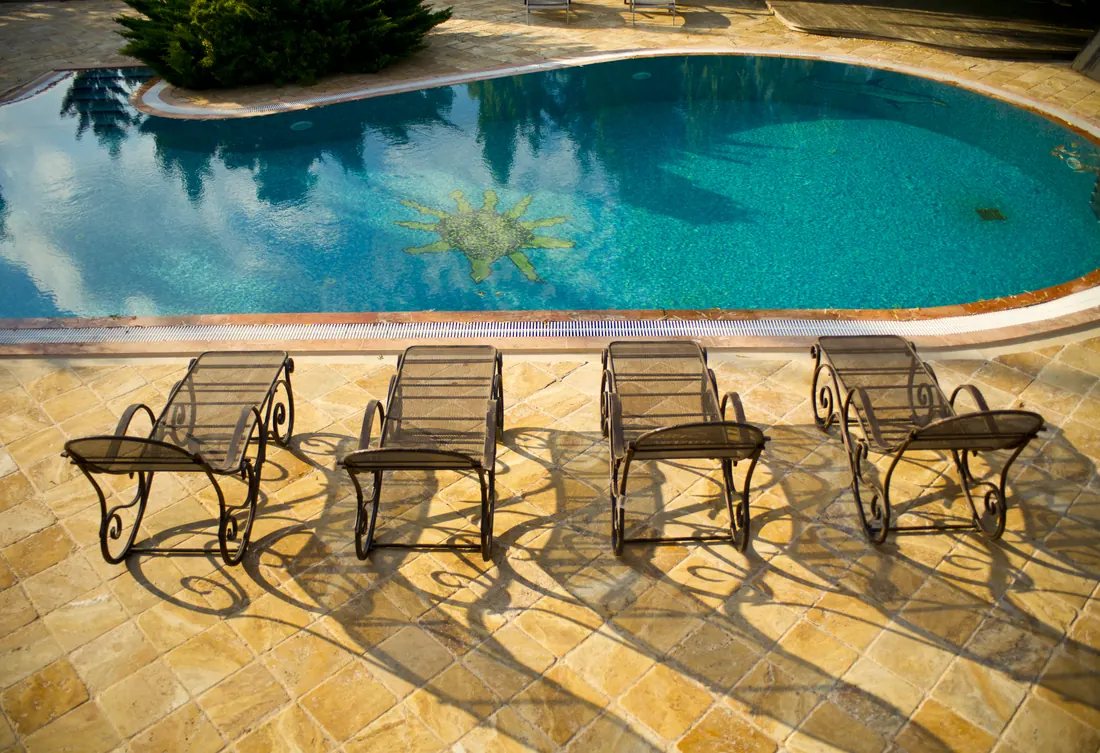 Oval inground pool with a sun mosaic design and poolside lounge chairs
