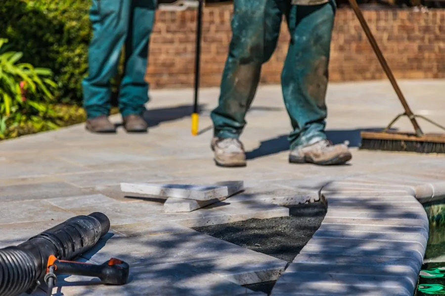 New paver patio construction beside inground pool